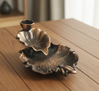 Bronze leaf-shaped candle holder on a wooden surface